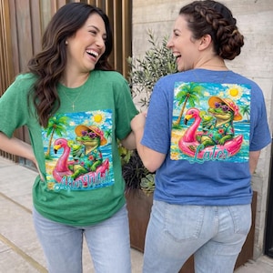 May include: Green and blue t-shirts with a tropical graphic featuring an alligator on a flamingo floatie, wearing sunglasses and a hat. The green shirt says "After While" and the blue shirt says "Later".