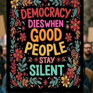 以下が含まれることがあります： 「DEMOCRACY DIES WHEN GOOD PEOPLE STAY SILENT」とカラフルな文字で書かれた黒い看板。赤、黄色、ターコイズ色の花と葉のデザインで装飾されています。木製の棒で支えられています。