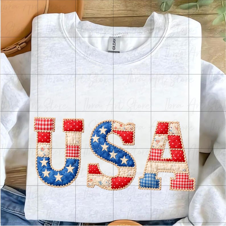 May include: White crew neck sweatshirt featuring the word "USA" in patchwork fabric. The letters use red, white, and blue patterns, including stars and stripes. A patriotic themed garment.