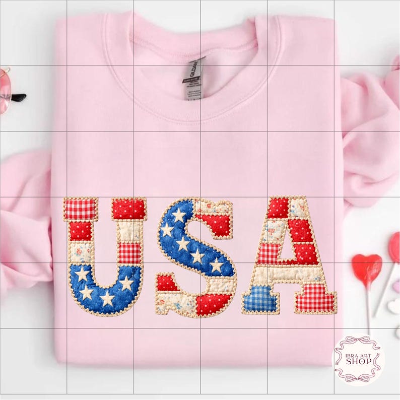 May include: A pale pink sweatshirt featuring the word "USA" in a patchwork design. The letters are crafted from fabric in red, white, and blue, incorporating star and stripe patterns.