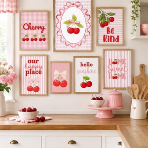 Peut inclure: Un ensemble de six cadres muraux illustrant des cerises sur des fonds à carreaux et rayures roses, avec les textes Cherry, Be Kind, our happy place, hello sunshine et HOME Sweet HOME, disposés au-dessus d'un comptoir de cuisine.