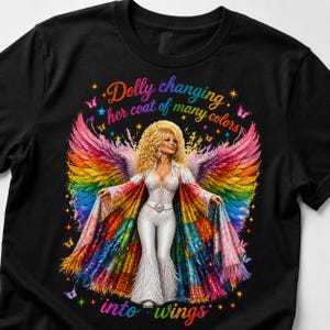 Puede incluir: Una camiseta negra con un gráfico de una figura rubia con grandes alas de colores del arcoíris, vistiendo un mono blanco con lentejuelas y un abrigo de patchwork. El texto dice "Dolly changing her coat of many colors into wings".
