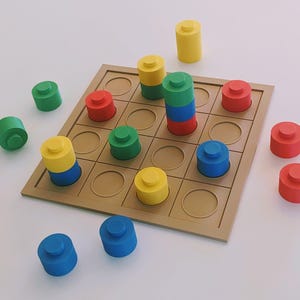 Könnte beinhalten: Ein Holzbrettspiel mit einem Raster aus kreisförmigen Feldern. Zylindrische Spielsteine in Rot, Grün, Blau und Gelb sind auf und um das Brett verstreut. Ein Stapel von Spielsteinen ist drei hoch.