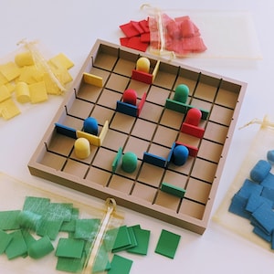 Puede incluir: Un juego de mesa de madera con un patrón de cuadrícula, con piezas de juego coloridas. El juego incluye piezas rojas, amarillas, verdes y azules, junto con pequeños componentes cuadrados y rectangulares. Las piezas están dispuestas en el tablero, sugiriendo juego.