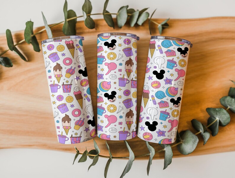 May include: Three cylindrical tumblers with a white background featuring a repeating pattern of colorful cartoon icons including ice cream cones, donuts, coffee cups, and black Mickey Mouse head silhouettes with pink and yellow accents.
