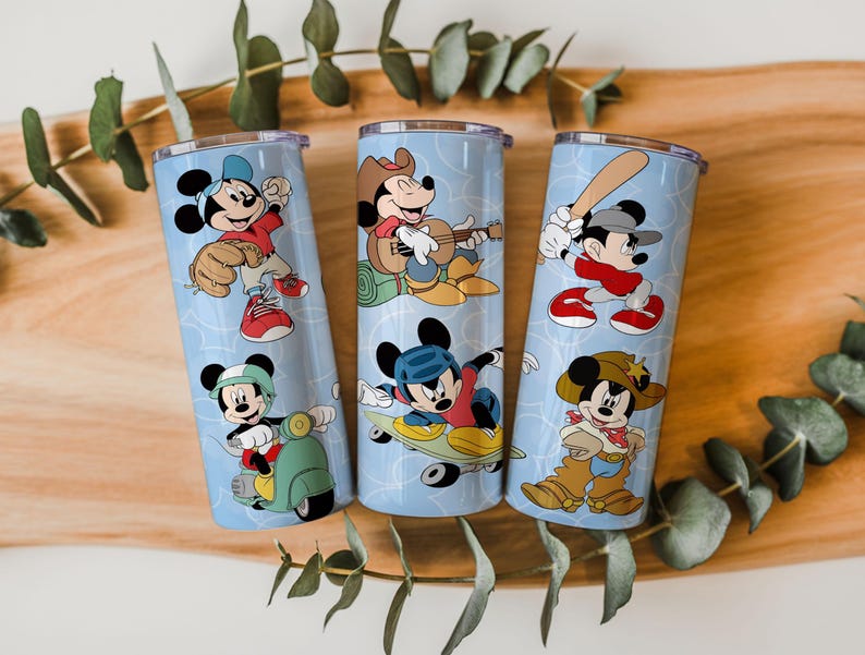 May include: Three cylindrical stainless steel tumblers with a light blue background featuring a repeating pattern of Mickey Mouse in various activities including baseball, playing guitar, riding a scooter, skateboarding, and wearing a cowboy outfit.