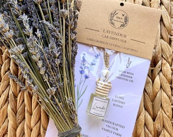 Può includere: Un mazzo di steli di lavanda viola essiccati accanto a un diffusore per auto alla lavanda in confezione trasparente. Il diffusore ha un tappo in legno, un cordino e un'etichetta con scritto M&A Family Farms Lavender Cuyama, CA. 8 ml.