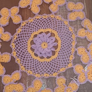 Hermoso tapete de crochet hecho a mano en morado y amarillo con mariposas a su alrededor