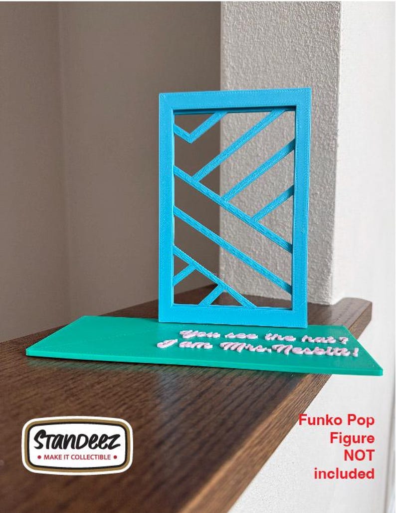 May include: A teal-colored display stand with a geometric design and a teal base. The base has the text "You see the hat? I am Mrs. Nesbitt!" in white. A logo for Standeez is in the lower left corner. The text "Funko Pop Figure NOT included" is in the lower right.