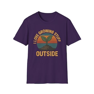 May include: A purple t-shirt with a graphic design featuring a sprout growing from soil against a sunset backdrop. The text reads "I LOVE GROWING STUFF OUTSIDE" in a circular arrangement.