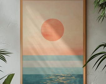 Puede incluir: Una impresión artística enmarcada que representa una puesta de sol sobre el océano. La obra presenta un gran sol color melocotón, bandas horizontales de azul claro y blanco, y un océano azul oscuro con reflejos brillantes. El marco es de madera marrón claro.