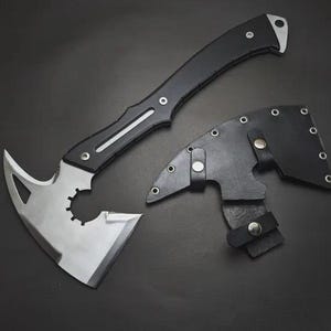 May include: A tactical axe with a black handle and a silver blade, accompanied by a black leather sheath. The axe features a unique blade design with a curved edge and a toothed section. The overall design is sleek and functional.