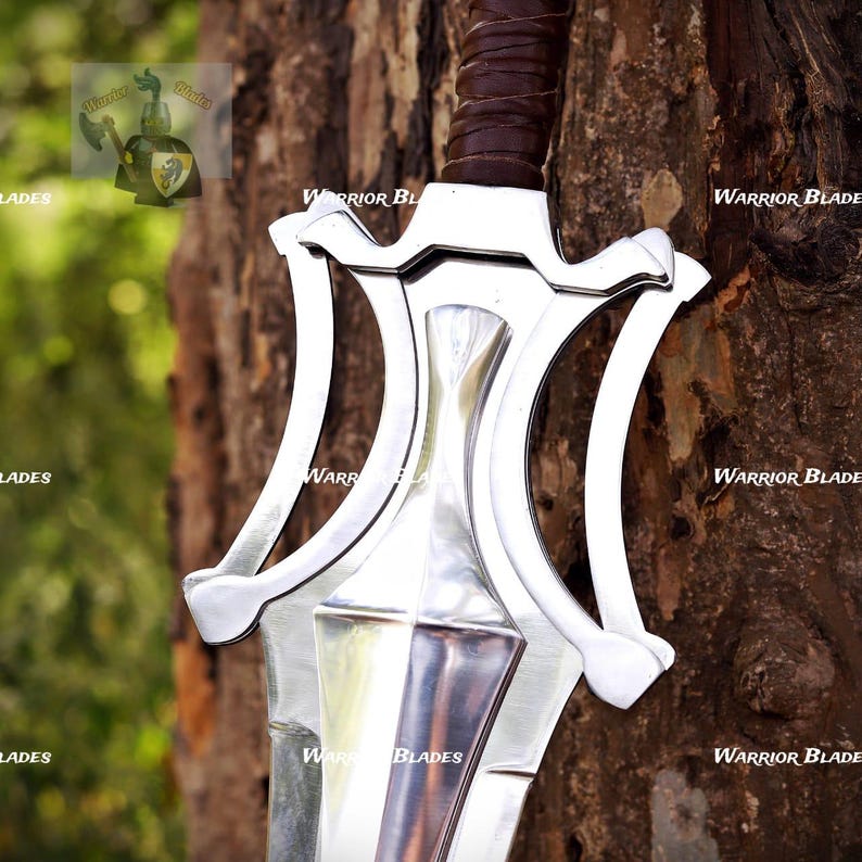 Pu&ograve; includere: Una spada in metallo color argento caratterizzata da una guardia complessa a curve multiple e un'impugnatura rivestita in pelle marrone. La lama &egrave; lucida e riflettente, con il testo Warrior Blades visibile sullo sfondo e sulla guardia.