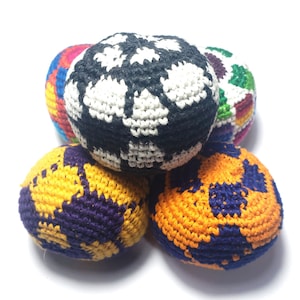 May include: A collection of five crocheted juggling balls in various colors. One ball is black and white, another is orange and blue, and others feature combinations of yellow, purple, and rainbow hues. The balls are arranged in a pile.