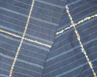 Puede incluir: Tela azul marino oscuro con rayas blancas y azul claro. La tela está decorada con patrones de cruces bordados de colores. El bordado presenta una variedad de colores, incluyendo rosa, amarillo, verde y azul, agregando un toque vibrante al diseño.