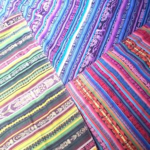 Peut inclure: Une collection de pièces de tissu pliées présentant des rayures verticales multicolores vibrantes. Les textiles affichent des motifs tissés complexes dans des tons de violet, bleu, jaune, vert et rouge, avec des motifs géométriques répétés intégrés.