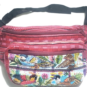 May include: A red fanny pack with a black adjustable strap. The main body has a striped pattern, and the front pocket features an embroidered design of colorful birds and foliage. The fanny pack has a zipper closure.