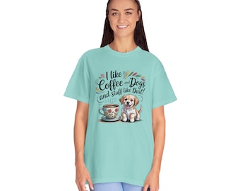 Pode incluir: Camiseta azul clara com o texto "I like Coffee and Dogs and stuff like that!". Apresenta uma imagem de desenho animado de uma xícara de café e um cachorro. A camiseta é feita de um material macio.