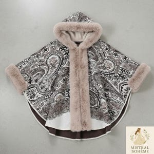 May include: A hooded cape with a paisley pattern in shades of brown, black, and white. The cape features faux fur trim around the hood, front opening, and cuffs. The bottom edge has a dark brown border.