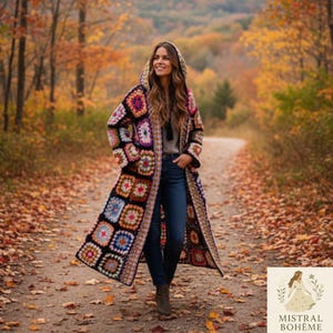 Könnte beinhalten: Ein langer Kapuzenmantel aus Häkelarbeit mit einem Patchwork-Design, das Quadrate in verschiedenen Farben wie Rosa, Blau und Lila aufweist. Der Mantel wird im Freien auf einem Weg getragen, der mit Herbstlaub bedeckt ist, mit einem Wald im Hintergrund. Der Mantel hat einen Bohemian-Stil.
