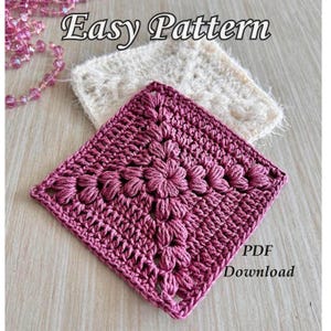 Peut inclure: Gros plan sur un carré crocheté rose foncé, avec un motif floral au centre. Le texte "Easy Pattern" est en haut et "PDF Download" en bas. Un deuxième carré crocheté blanc cassé est en arrière-plan.