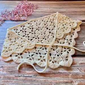 May include: A cream-coloured, handmade crochet bonnet with a scalloped edge and tie closure. The bonnet features an openwork design and is displayed on a wooden surface. The text "Instant Download PDF" is visible at the bottom.
