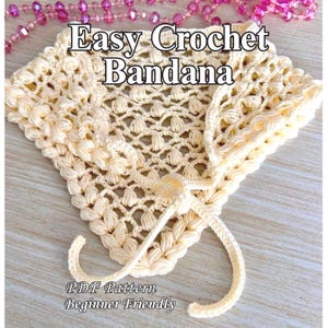 May include: Cream-colored crochet bandana with a textured, openwork design. The text "Easy Crochet Bandana" is displayed at the top, with "PDF Pattern Beginner Friendly" at the bottom. The bandana has tie closures.