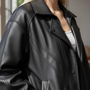 Puede incluir: Chaqueta negra de cuero sint&eacute;tico con cuello, cierre de cremallera y cierre de bot&oacute;n. La chaqueta presenta detalles de costura decorativos y un bolsillo. Una prenda de abrigo cl&aacute;sica.