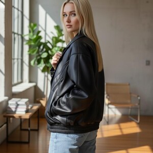 Puede incluir: Chaqueta bomber de cuero negro con dobladillo y pu&ntilde;os de canal&eacute;. La chaqueta tiene un dise&ntilde;o cl&aacute;sico con cuello, cierre de cremallera y bolsillos. La chaqueta se lleva con vaqueros azules.