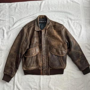 Back view of distressed brown leather bomber jacket showing natural texture and worn-in vintage finish — handmade real leather outerwear.