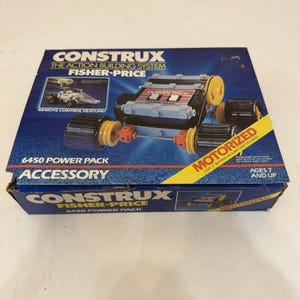 Puede incluir: Una caja del sistema de construcción Fisher-Price Construx 6450 Power Pack. El empaque azul muestra un vehículo motorizado con ruedas negras, detalles amarillos y conectores naranjas. El texto incluye Construx y Motorized.
