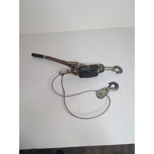 May include: A brown and black come-along tool with a black handle and two hooks. A silver cable connects the main body to a pulley with a hook. The tool is designed for pulling or lifting heavy objects.