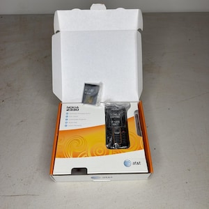 Peut inclure: Un téléphone portable Nokia 2330 dans une boîte de vente blanche et orange avec un logo AT&T. Le téléphone est noir avec un autocollant sur l'écran indiquant TXTNG & DRIVNG IT CAN WAIT. Une batterie est incluse dans un sachet plastique à l'intérieur.