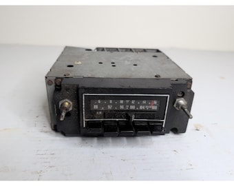 Può includere: Una vecchia autoradio con frontalino nero e cassa in metallo argentato. La radio ha un quadrante delle frequenze con impostazioni AM e FM, pulsanti e manopole. La gamma di frequenza è da 88 a 108.