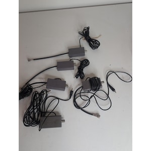 以下が含まれることがあります： 5つの灰色の長方形の電子信号アダプターのセット。それぞれの一端に金属製のコネクタポートがあり、もう一端には対応するプラグが付いた黒い電気ケーブルが接続されており、グループとして配置されています。
