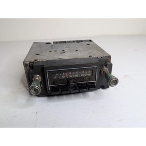 Peut inclure: Poste de radio de voiture vintage avec un boîtier en métal argenté et une façade noire. La façade comporte un cadran de fréquences et des boutons. Des boutons sont de chaque côté. La radio affiche les fréquences de 88 à 108.