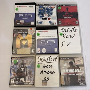 May include: A collection of nine PlayStation 3 video game cases arranged in a three-by-three grid. Titles include Final Fantasy XIII, NHL 12, Dead Island, Metro Last Light, Medal of Honor Warfighter, Saints Row IV, Destiny, Injustice, and The Walking Dead.