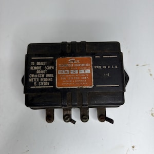 Puede incluir: Transmisor de tacómetro Sun negro con una etiqueta naranja y blanca. La etiqueta dice "Sun Tachometer Transmitter" y "Made in U.S.A." El dispositivo tiene múltiples terminales e instrucciones de ajuste.