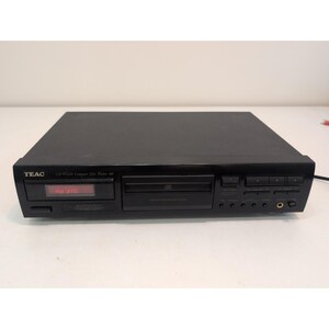 Peut inclure: Un lecteur de disque compact TEAC CD-P1120 noir avec un tiroir de chargement frontal, un écran d'affichage numérique indiquant le texte no disc, plusieurs boutons de commande et une prise casque sur le côté droit du panneau avant.