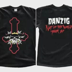 May include: Black t-shirts featuring a skull design within a cross shape, with a red outline and accents. The second shirt displays the text "DANZIG Not of This World Tour 89" in white and red. The shirts are likely band merchandise.