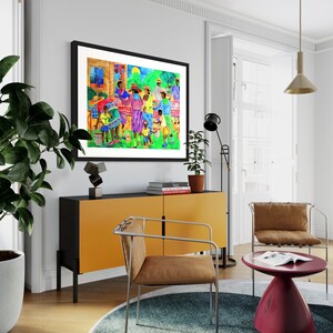 May include: A framed painting depicting a group of people gathered outdoors, with vibrant colors and a lively atmosphere. The painting features a mix of adults and children, all dressed in colorful clothing. The scene is set against a backdrop of lush greenery and a sunny sky.