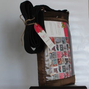 May include: A brown crossbody bag with a clear plastic window displaying a collage of colourful images. The bag has a black adjustable strap and a small tag with the text "Four Seasons" and a butterfly logo.