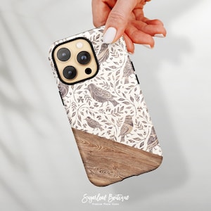 May include: A white phone case with a wood grain design and a pattern of birds and branches. The case has a black camera bump with three lenses.
