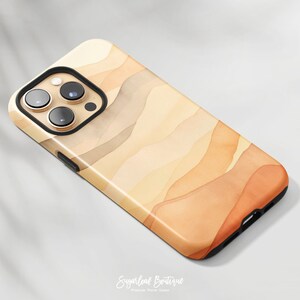 May include: A phone case with a watercolor-style design featuring abstract shapes in shades of orange, brown, and beige. The case is designed for an iPhone.