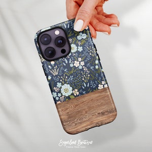 May include: A blue and white floral phone case with a wood grain design on the bottom half. The case is made for an iPhone with a triple lens camera.