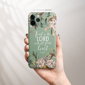 Könnte beinhalten: Eine salbeigrüne Handyhülle mit floralen und Pilz-Illustrationen. Die Hülle zeigt den Text "Trust in the LORD with all your heart" in weißer Schrift. Die Hülle ist mit Blumen, Blättern und Pilzen verziert.