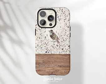 May include: A phone case with a white background and a pattern of brown and gray leaves and a small bird. The bottom half of the case is a wood grain pattern.