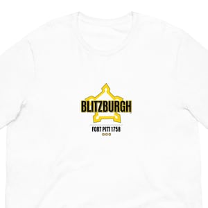 May include: White t-shirt with a yellow and black graphic that reads "BLITZBURGH" above "FORT PITT 1758". The design is a stylized star shape. The shirt is made of a soft material.