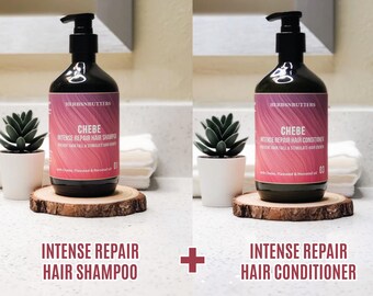 May include: Two black bottles of hair care products, shampoo and conditioner, with pink labels and black pumps. The labels read "CHEBE INTENSE REPAIR HAIR SHAMPOO" and "CHEBE INTENSE REPAIR HAIR CONDITIONER". The bottles sit on wooden coasters.