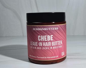 May include: A jar of Chebe Leave-In Hair Butter by HerbsnButters. The label is pink and features the product name and the words "RETAIN AND LOCKS IN MOISTURE". The jar is brown with a black lid. The product contains Chebe, Flaxseed & Horsetail oil.